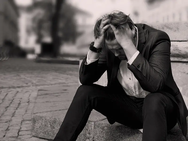 Fekete-fehér képen férfi kezébe temeti fejét